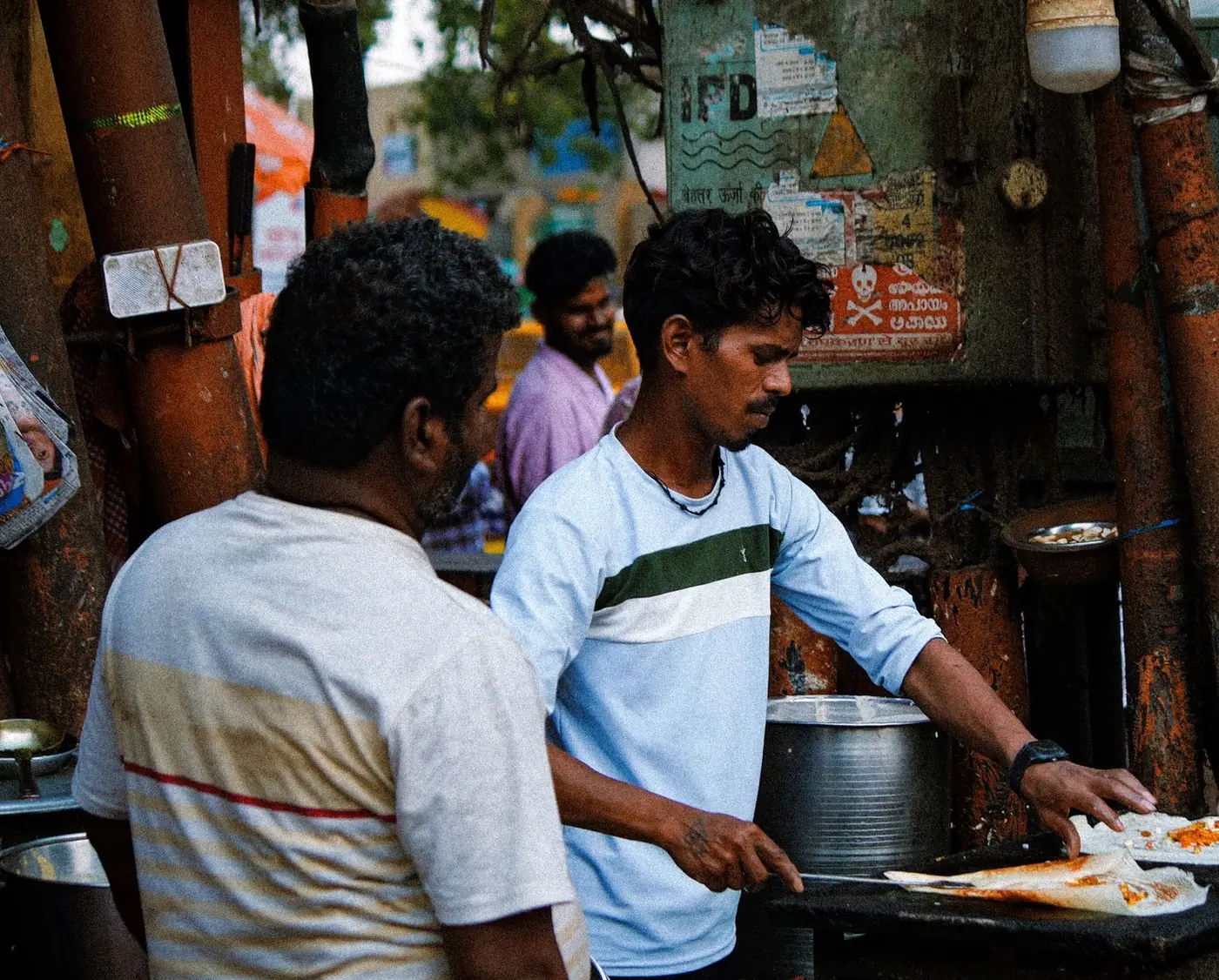 A cook making dosa at a street stall